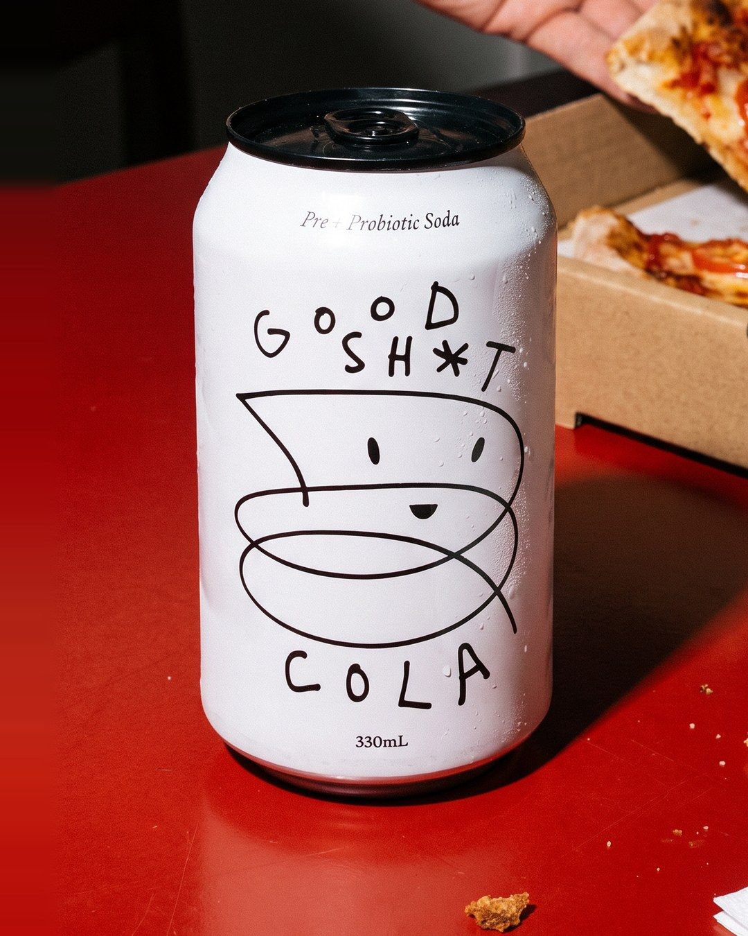 The same can on a red table with pizza night behind it