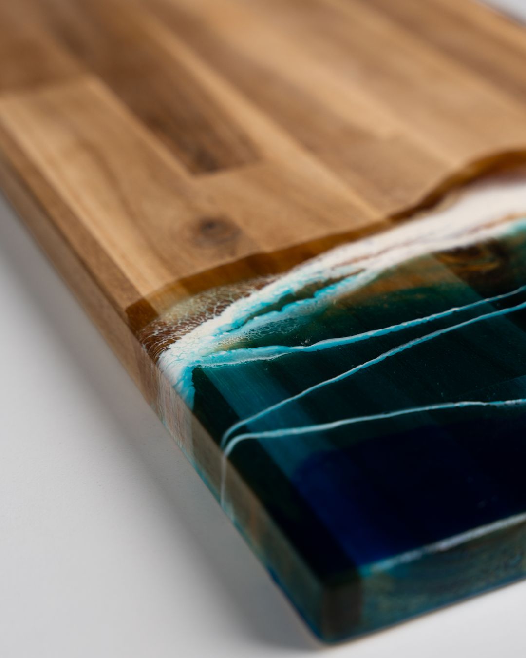 Close-up of a timber serving board edged in teal resin